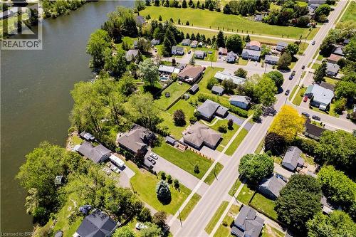 Aerial perspective highlighting a waterfront property with a tree-lined perimeter and lush green lawns - 100 Mechanic Street W, Waterford, ON - Outdoor With Body Of Water With View