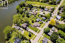 Aerial perspective highlighting a waterfront property with a tree-lined perimeter and lush green lawns - 