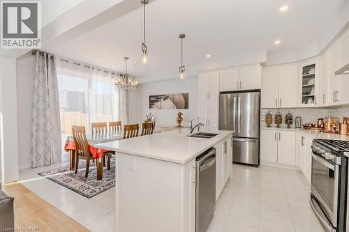 Kitchen with a center island with sink, white cabinetry, hanging light fixtures, and appliances with stainless steel finishes - 53 Mackay Drive, Woodstock, ON - Indoor Photo Showing Kitchen With Double Sink With Upgraded Kitchen