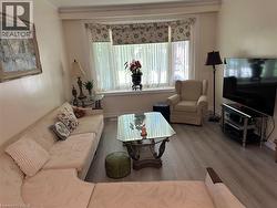 Bright living area featuring wood-finish flooring, a large bay window, and crown molding - 