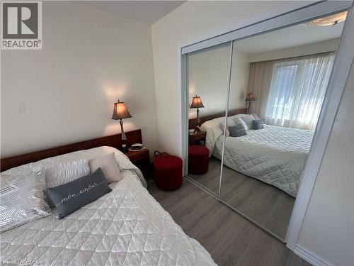 Bedroom featuring light wood-finish flooring, white walls, and a large mirrored closet - 1571 Muir Road, Mississauga, ON 
