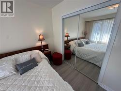 Bedroom featuring light wood-finish flooring, white walls, and a large mirrored closet - 