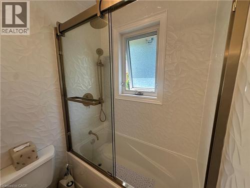 Bathtub and shower combination featuring a glass enclosure with bronze-finish hardware - 1571 Muir Road, Mississauga, ON 