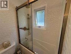 Bathtub and shower combination featuring a glass enclosure with bronze-finish hardware - 