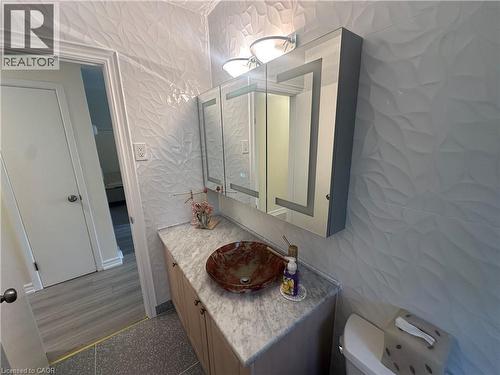 Vanity area featuring a vessel sink, stone countertop, wood-finish cabinetry, and a mirrored medicine cabinet - 1571 Muir Road, Mississauga, ON 