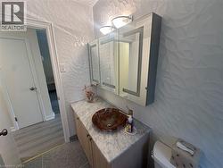 Vanity area featuring a vessel sink, stone countertop, wood-finish cabinetry, and a mirrored medicine cabinet - 
