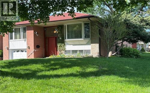Red brick and stone facade with a red main entry door, white garage door, and a prominent bay window - 1571 Muir Road, Mississauga, ON 