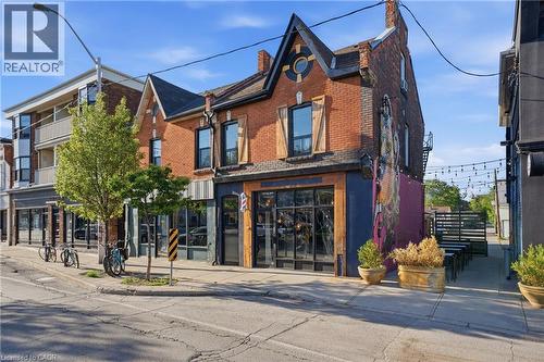 Brick facade building featuring a gabled roofline with a circular window, wood shutters on upper-story windows, and a large storefront display window - 355 Barton Street E, Hamilton, ON - Outdoor