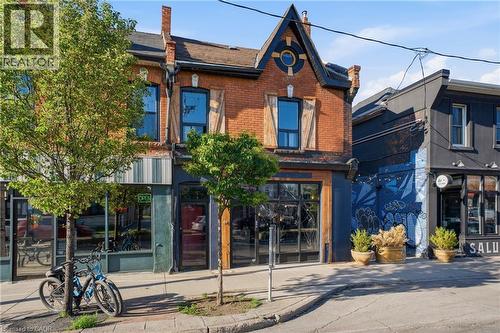Brick facade building featuring a gabled roofline with decorative trim, large storefront windows, and prominent upper-level windows with wooden shutters - 355 Barton Street E, Hamilton, ON - Outdoor
