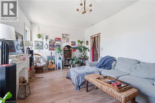 Spacious living area featuring wood-finish flooring, a white brick fireplace surround, and a classic chandelier - 355 Barton Street E, Hamilton, ON - Indoor Photo Showing Bedroom