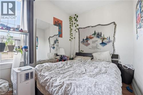 Bright room featuring a large window with white trim, hard surface flooring, and light-toned walls - 355 Barton Street E, Hamilton, ON - Indoor Photo Showing Bedroom