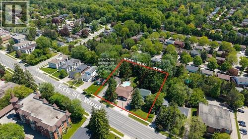 Aerial view of a residential area with dense tree coverage, featuring a property outlined in red - 395 Erb Street, Waterloo, ON 