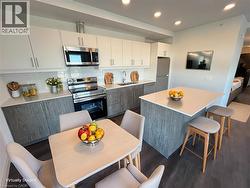 AI staged Modern kitchen featuring two-tone cabinetry, stainless steel appliances, white subway tile backsplash, and dark wood-finish flooring - 