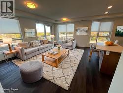 AI staged Expansive living space featuring dark wood-finish flooring, numerous large windows, and recessed ceiling lighting - 