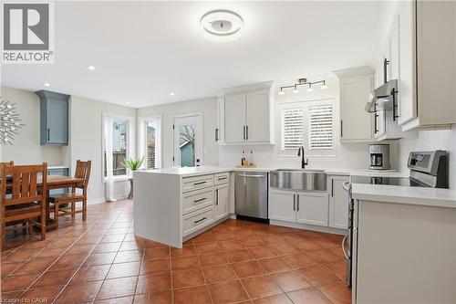 Kitchen with stainless steel appliances, a peninsula, light tile patterned flooring, recessed lighting, and white cabinetry - 56 Mccaffery Crescent, St. Catharines, ON - Indoor Photo Showing Other Room