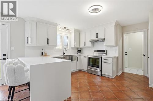 Kitchen featuring a peninsula, a kitchen breakfast bar, stainless steel electric stove, white cabinets, and light tile patterned flooring - 56 Mccaffery Crescent, St. Catharines, ON - Indoor Photo Showing Kitchen