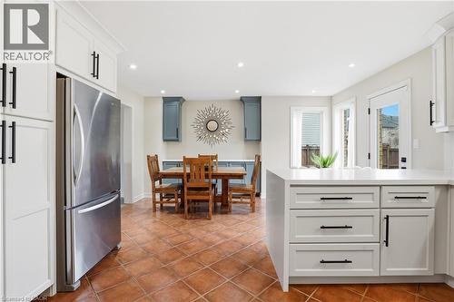 Kitchen featuring freestanding refrigerator, a peninsula, recessed lighting, dark tile patterned flooring, and white cabinets - 56 Mccaffery Crescent, St. Catharines, ON - Indoor