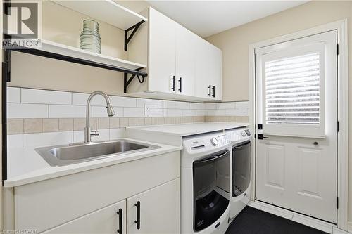 Laundry area featuring cabinet space, washing machine and clothes dryer, and light tile patterned flooring - 56 Mccaffery Crescent, St. Catharines, ON - Indoor Photo Showing Laundry Room
