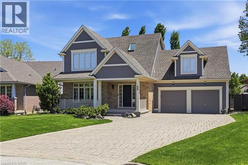 Grey-toned exterior featuring brick and shake siding, a covered front porch, a two-car garage, an interlocking paver driveway, and a dormer window - 56 Mccaffery Crescent, St. Catharines, ON - Outdoor With Facade