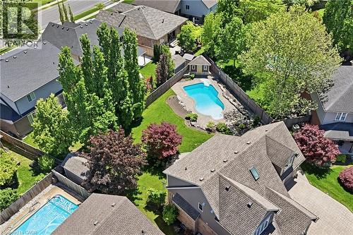 Backyard oasis featuring an irregular-shaped inground pool with stone coping, a dedicated pool house, manicured lawn areas, and mature landscaping - 56 Mccaffery Crescent, St. Catharines, ON - Outdoor With In Ground Pool With Deck Patio Veranda