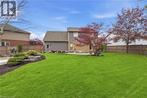 Expansive backyard featuring a manicured lawn, established landscaping, mature trees, a privacy fence, and a stone patio - 56 Mccaffery Crescent, St. Catharines, ON - Outdoor