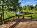 Expansive wooden deck overlooking a serene body of water, bordered by lush green foliage and mature trees - 1006 Hurdville Road, Mckellar, ON  - Outdoor With Deck Patio Veranda With View 