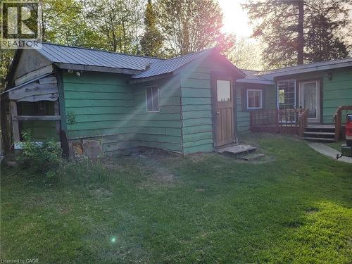 Green-sided dwelling with a metal roof and a separate shed featuring a wood door - 1006 Hurdville Road, Mckellar, ON - Outdoor