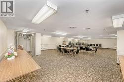 Spacious common area featuring patterned carpeting, fluorescent overhead lighting, and white walls - 