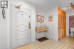 White paneled entry door with brass hardware, tile flooring, and wood-finish louvered closet doors - 