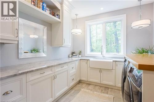 Laundry room featuring an apron-front sink, white cabinetry with silver hardware, light-toned countertops, and a wood-finish floor - 1521 Emily Lane, Severn, ON - Indoor Photo Showing Other Room