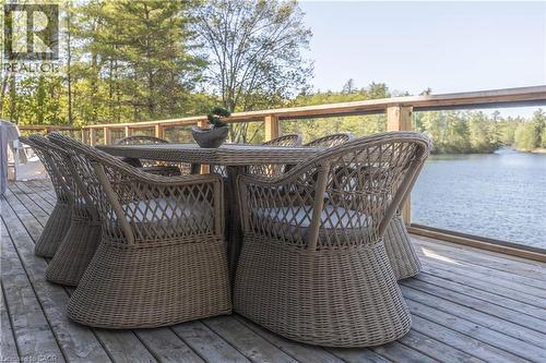 Expansive wood deck with a clear glass railing overlooking a body of water and mature trees - 1521 Emily Lane, Severn, ON - Outdoor With Deck Patio Veranda With Exterior