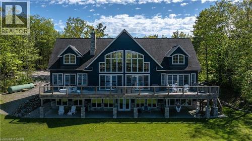 Expansive residence featuring a multi-level deck, stone chimney, and numerous windows - 1521 Emily Lane, Severn, ON - Outdoor With Deck Patio Veranda With Facade