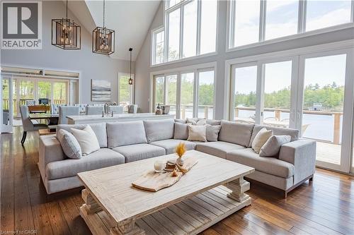 Vaulted ceilings with exposed beams complement the full wall of windows and glass doors - 1521 Emily Lane, Severn, ON - Indoor Photo Showing Living Room
