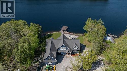 Waterfront residence featuring a dark blue exterior with white trim, multiple dormer windows, and a dark shingle roof - 1521 Emily Lane, Severn, ON - Outdoor With Body Of Water With View