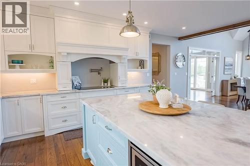 Kitchen featuring a light blue center island with a stone countertop, white cabinetry with stone countertops, wood-finish flooring, and a pot filler faucet - 1521 Emily Lane, Severn, ON - Indoor Photo Showing Kitchen