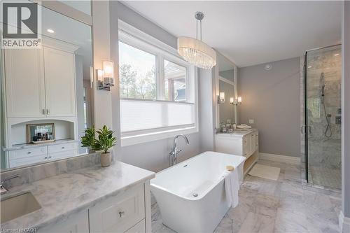Freestanding soaking tub with chrome fixtures, glass-enclosed shower, dual vanity with undermount sinks and stone countertops, and a crystal chandelier - 1521 Emily Lane, Severn, ON - Indoor Photo Showing Bathroom
