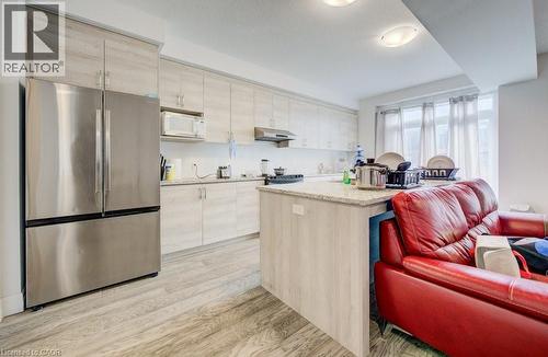 Kitchen featuring light wood-finish cabinetry, a stainless steel French-door refrigerator, and a matching microwave - 32 Faith Street Unit# 19, Cambridge, ON - Indoor Photo Showing Kitchen