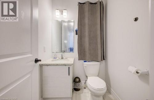 Contemporary bathroom featuring a white vanity with a speckled countertop, a rectangular mirror, and a two-light vanity fixture - 32 Faith Street Unit# 19, Cambridge, ON - Indoor Photo Showing Bathroom
