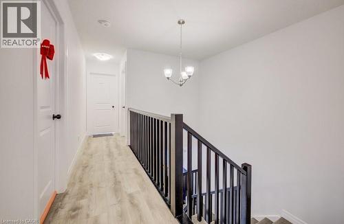 Hallway with wood-finish flooring, white walls, and a contemporary chandelier - 32 Faith Street Unit# 19, Cambridge, ON - Indoor Photo Showing Other Room