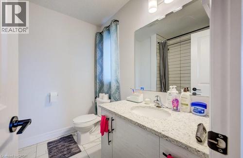 Bathroom featuring a vanity with a light-toned speckled countertop, an undermount sink, and a framed mirror - 32 Faith Street Unit# 19, Cambridge, ON - Indoor Photo Showing Bathroom