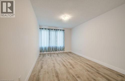 Light-filled room featuring wood-finish flooring, neutral wall paint, white baseboards, and a flush-mount ceiling light - 32 Faith Street Unit# 19, Cambridge, ON - Indoor Photo Showing Other Room