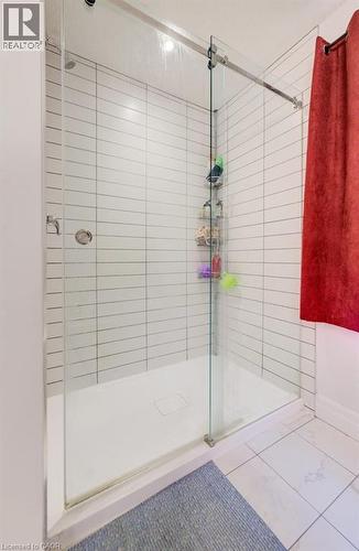 Walk-in shower featuring a frameless glass enclosure with a sliding door, white rectangular subway tile, a recessed shower niche, and a white shower pan - 32 Faith Street Unit# 19, Cambridge, ON - Indoor Photo Showing Bathroom