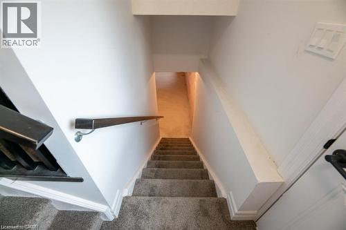 Carpeted staircase with a wood-finish handrail and white wall trim - 32 Faith Street Unit# 19, Cambridge, ON - Indoor Photo Showing Other Room