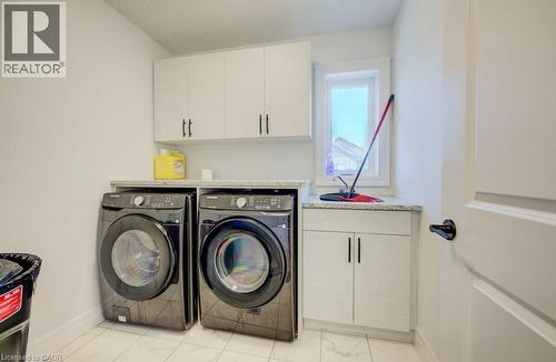 Dedicated laundry space featuring white cabinetry, gray speckled countertops, an integrated sink, and a window - 32 Faith Street Unit# 19, Cambridge, ON - Indoor Photo Showing Laundry Room