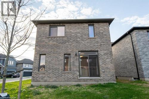Exterior rear elevation featuring gray brick masonry, multiple windows, a sliding glass door, and dark gutters - 32 Faith Street Unit# 19, Cambridge, ON - Outdoor