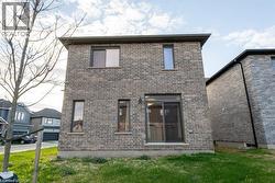 Exterior rear elevation featuring gray brick masonry, multiple windows, a sliding glass door, and dark gutters - 