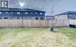 Fenced backyard featuring a newly planted tree, green space, and privacy fencing - 