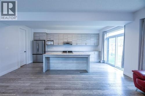 Contemporary kitchen featuring light wood-finish cabinetry, stainless steel appliances, a center island with a sink, and granite countertops - 32 Faith Street Unit# 19, Cambridge, ON - Indoor