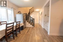 Bright interior featuring wood-finish flooring, a contemporary staircase with dark risers and railings, and a built-in cabinetry unit with a light-colored countertop - 