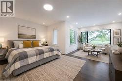 Spacious room featuring dark wood-finish flooring, recessed lighting, and a large window framing exterior greenery - 